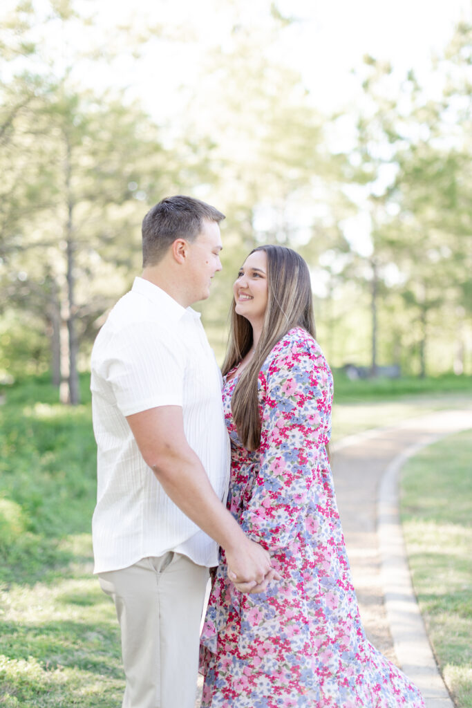 engaged couple standing face to face holding hands